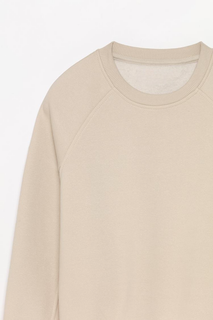 Zoomed-in view of a women's beige basic cropped sweatshirt, highlighting the fabric texture, stitching details, and cropped design.