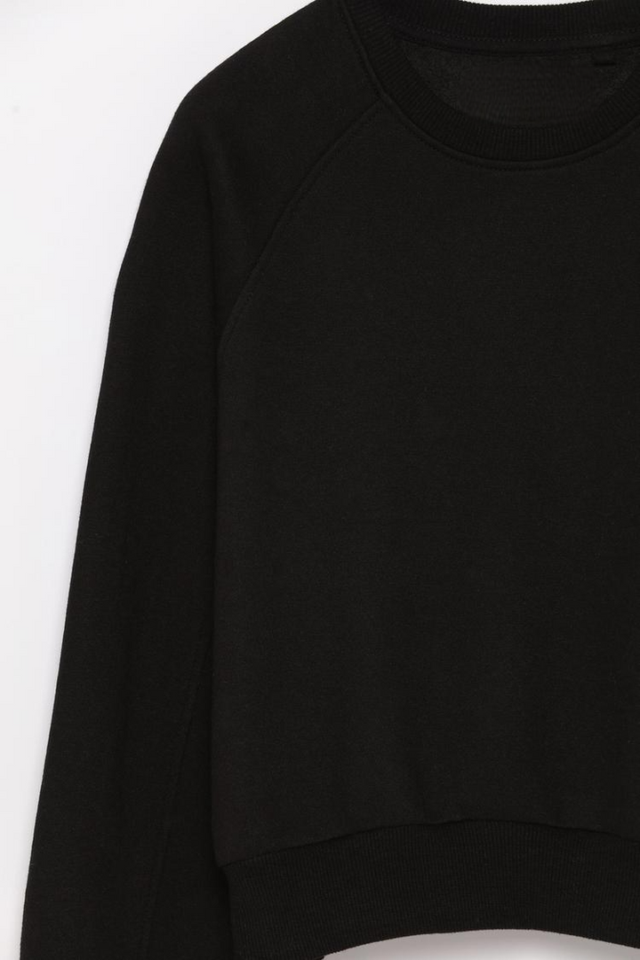 Zoomed-in view of a women's black basic cropped sweatshirt, showcasing the fabric texture, neckline, and stitching details.