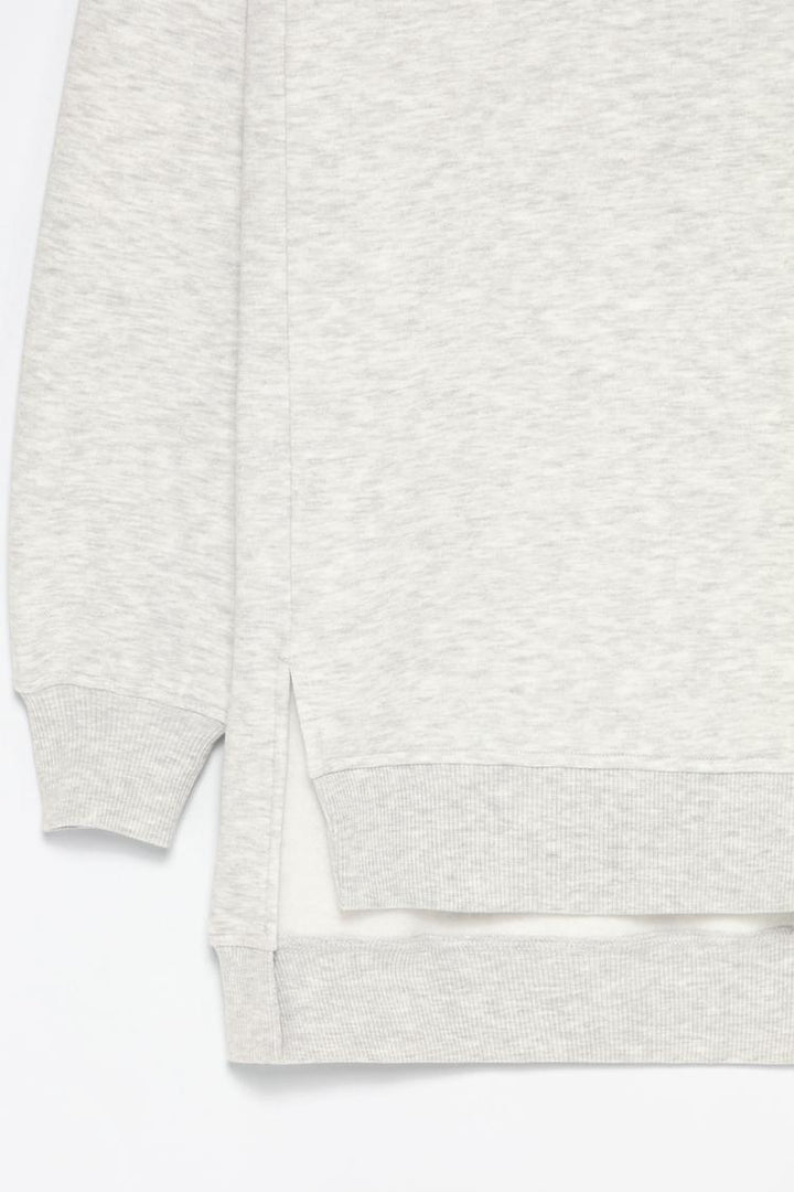Zoomed-in view of a women's grey oversized sweatshirt, highlighting the asymmetric design, fabric texture, and stitching details.