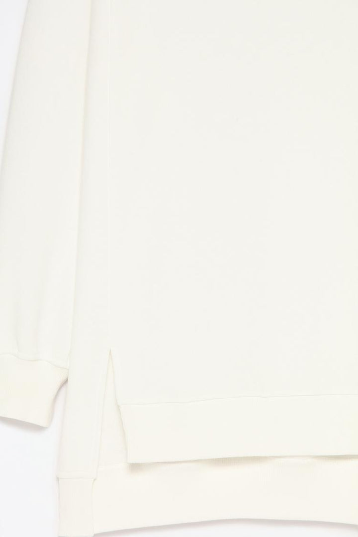 Zoomed-in view of a women's white oversized sweatshirt, showcasing the asymmetric design and fabric texture for a detailed look.