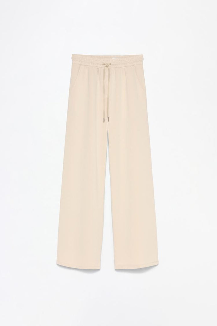 Product view of beige flowing sports trousers featuring the fabric and details.