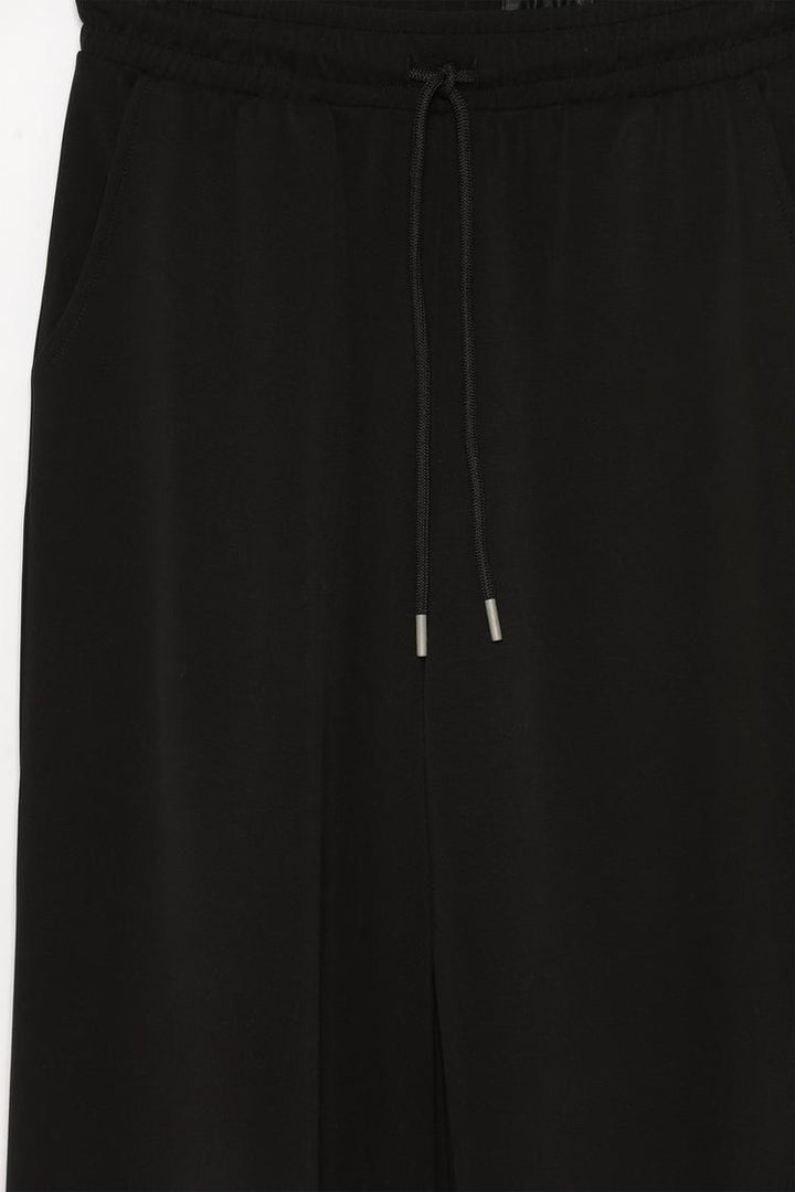 Product view of black flowing sports trousers featuring lightweight fabric.