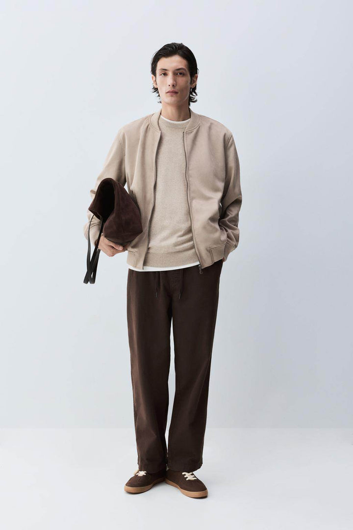 Full body front view of man wearing beige faux suede bomber

