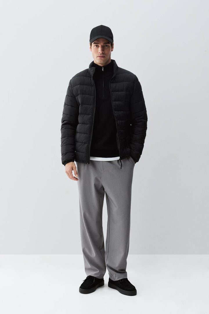 Full body front view of man wearing black lightweight puffer jacket

