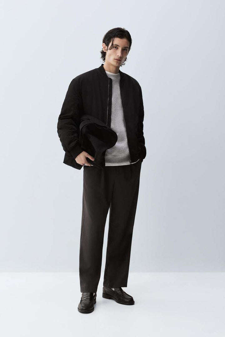 Full body front view of man wearing black padded bomber jacket

