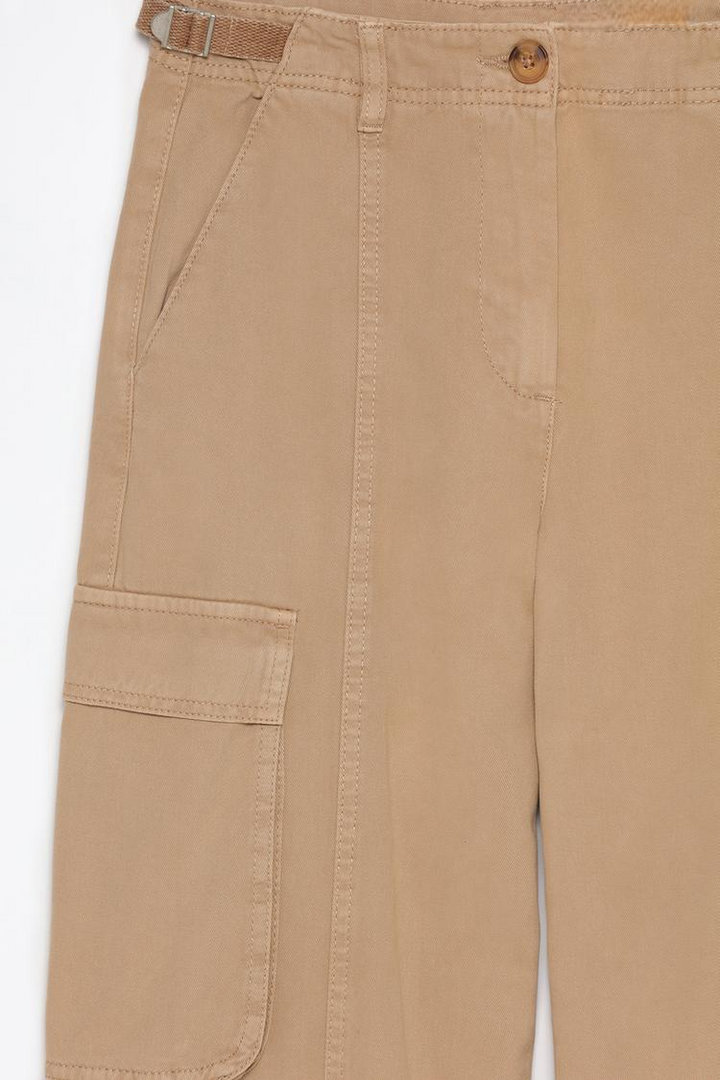 Close-up of the beige cargo trousers, emphasizing the premium fabric and intricate buckle design.