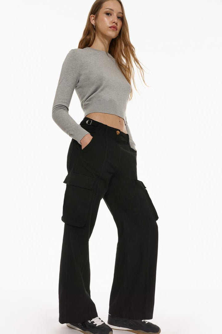 Side view of the black cargo trousers, highlighting their spacious pocket design and adjustable buckle straps.