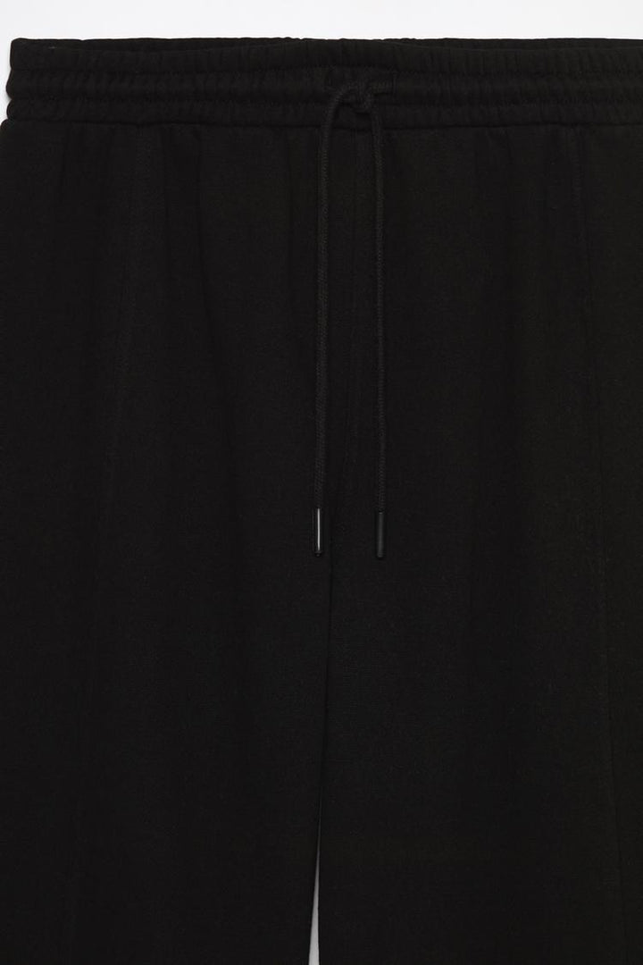 Close-up shot of the black oversize plush trousers, showing the fabric texture, stitching, and overall details of the trousers.