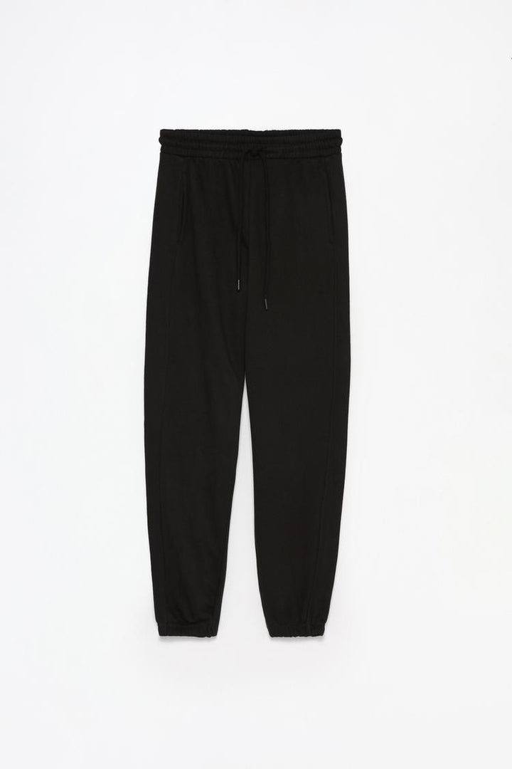 Full product image of the black oversized tracksuit trousers, displaying the overall design and material.