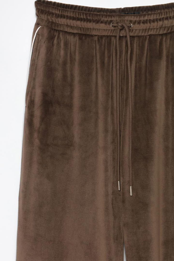 Product view of brown oversized velvet trousers showing fabric and styling.
