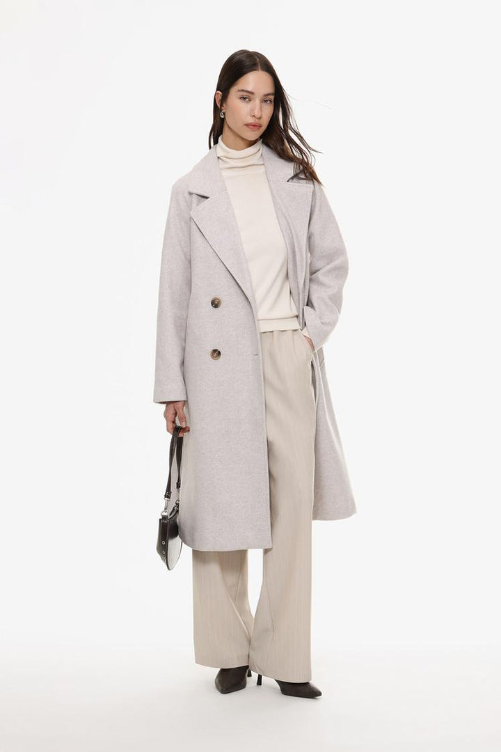 Full-body view of beige straight-fit trousers, styled to show versatility and elegance
