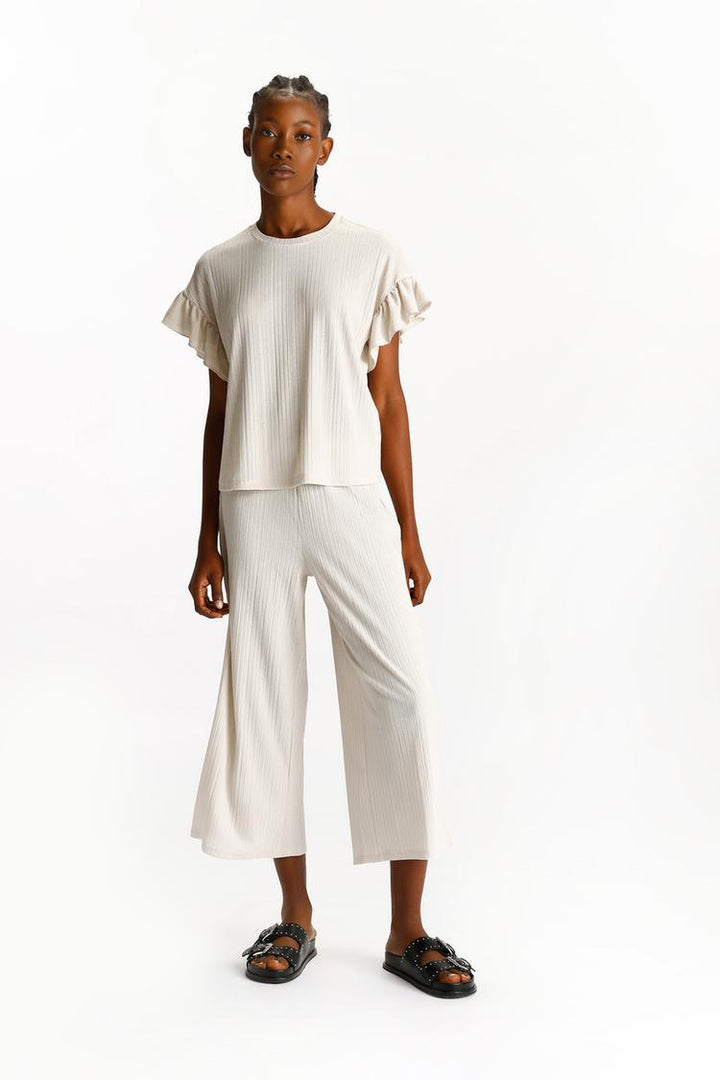 Full-body image of the beige textured culottes, illustrating their complete length and drape.