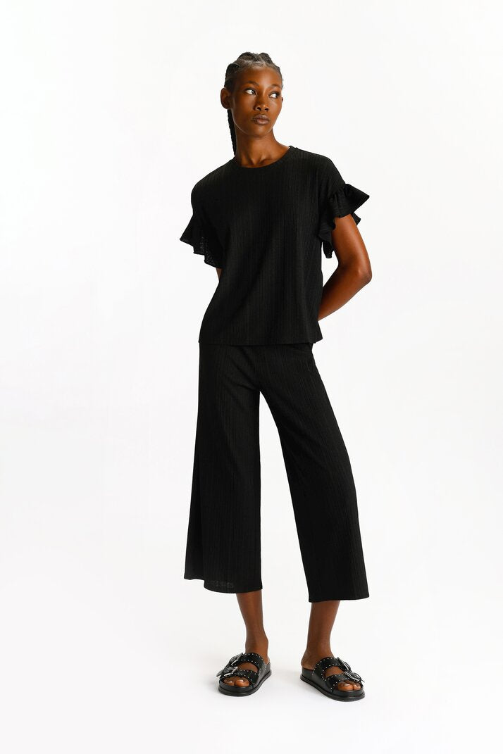 Rear view of the black textured culottes, emphasizing their smooth and tailored finish.