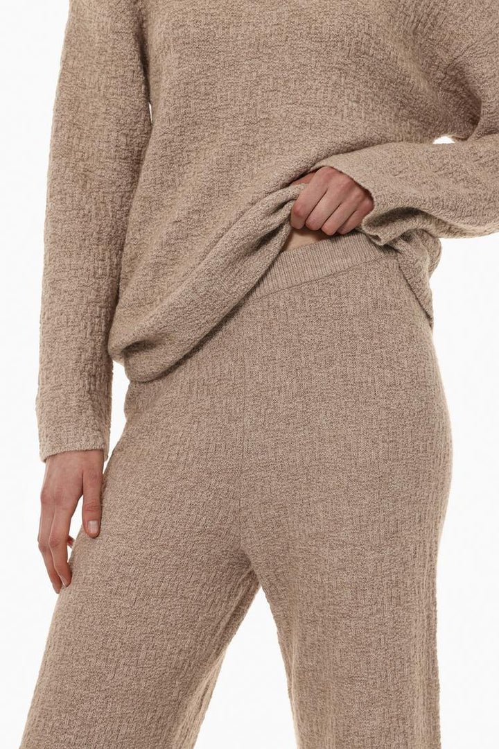 Styled outfit featuring the beige textured knit trousers, demonstrating their versatility.