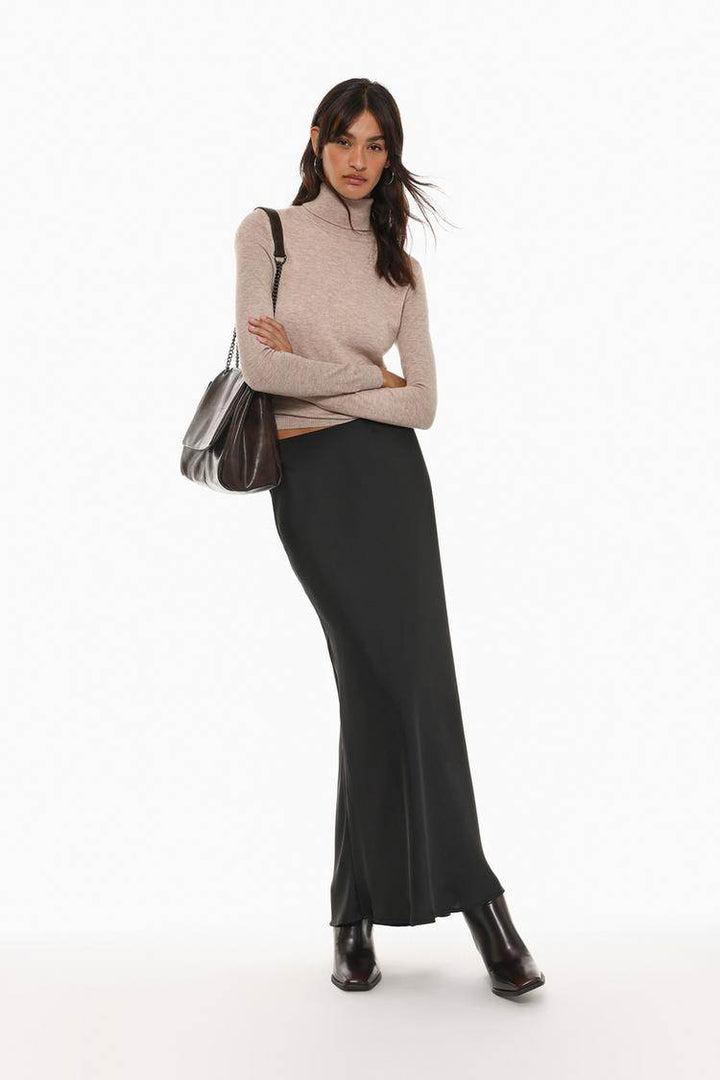 Full body front view of woman wearing beige turtleneck sweater

