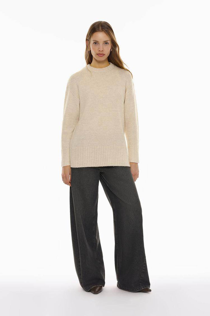 Full body front view of woman wearing beige long soft sweater

