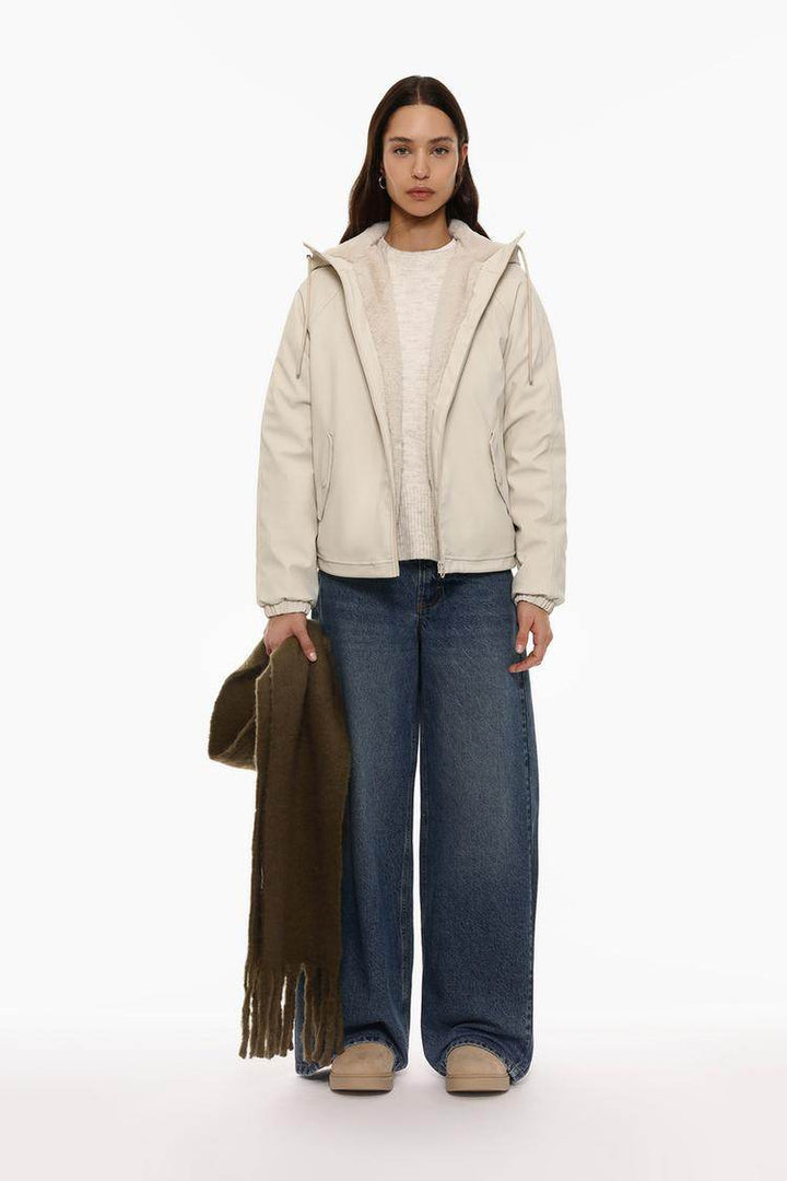 Full body front view of woman wearing beige rubberised parka

