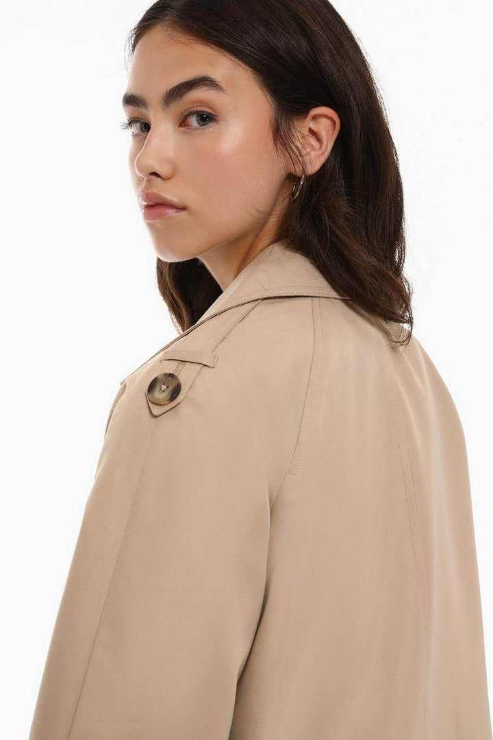 Side view of the women's beige short oversize trench coat

