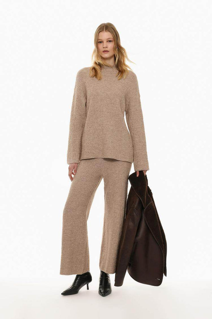 Full body front view of woman wearing beige textured knit sweater

