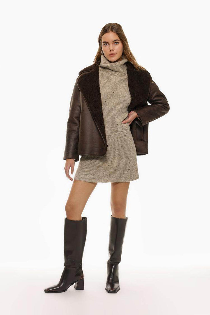 Full body front view of woman wearing beige turtleneck sweater

