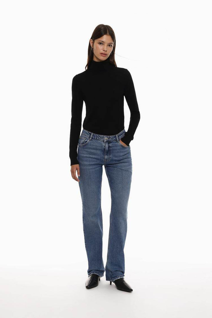 Full body front view of woman wearing black turtleneck sweater

