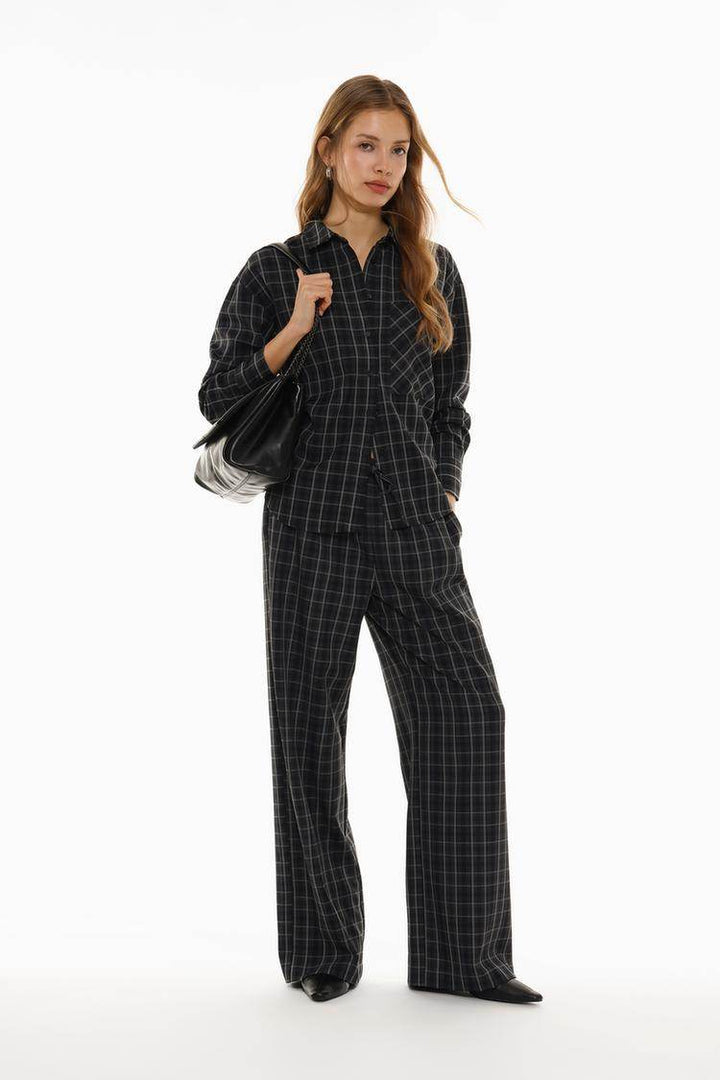 Full body front view of woman wearing black checked shirt

