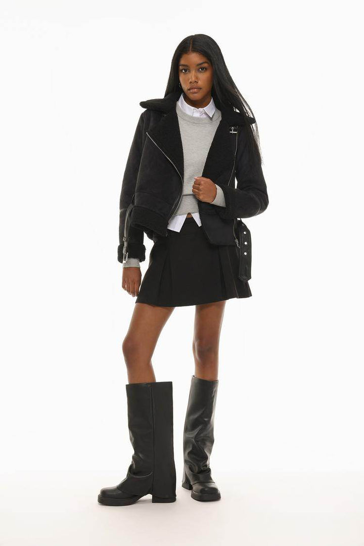 Full body front view of woman wearing black crossover jacket

