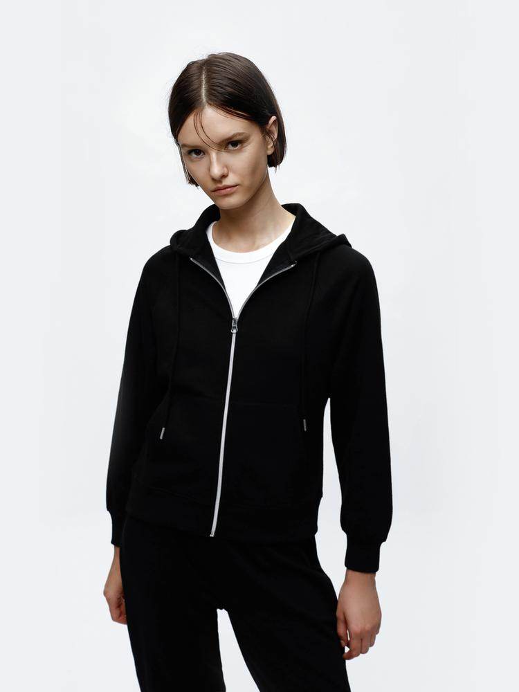 Full body front view of woman wearing black hooded jacket

