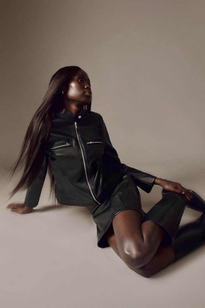 Model sitting and wearing black leather effect jacket

