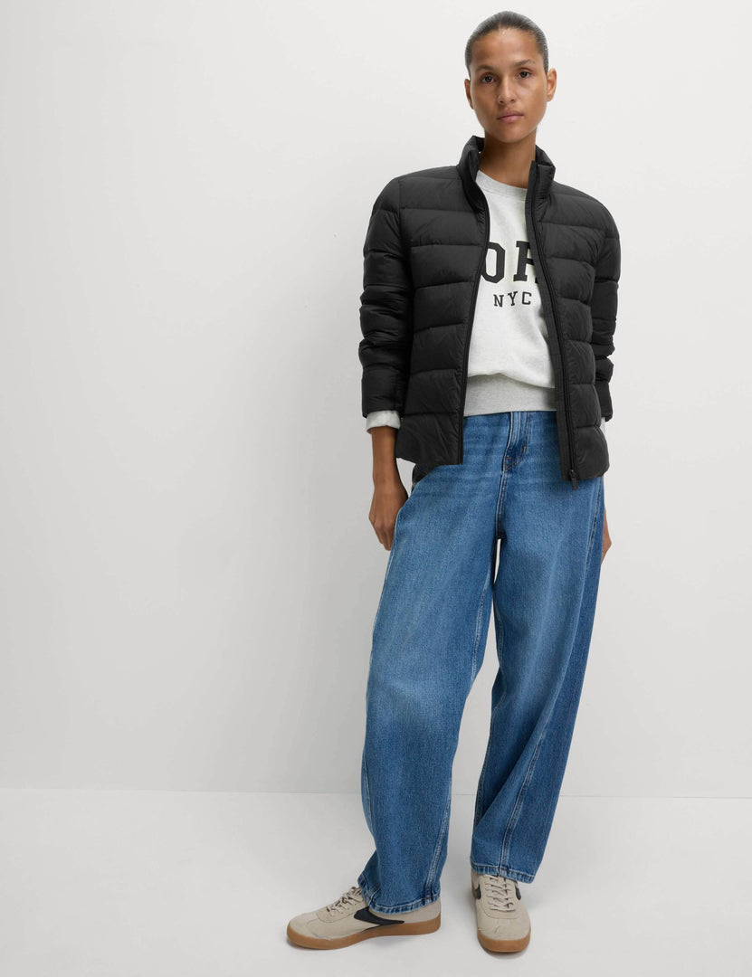 Full body front view of a woman wearing a black puffer jacket

