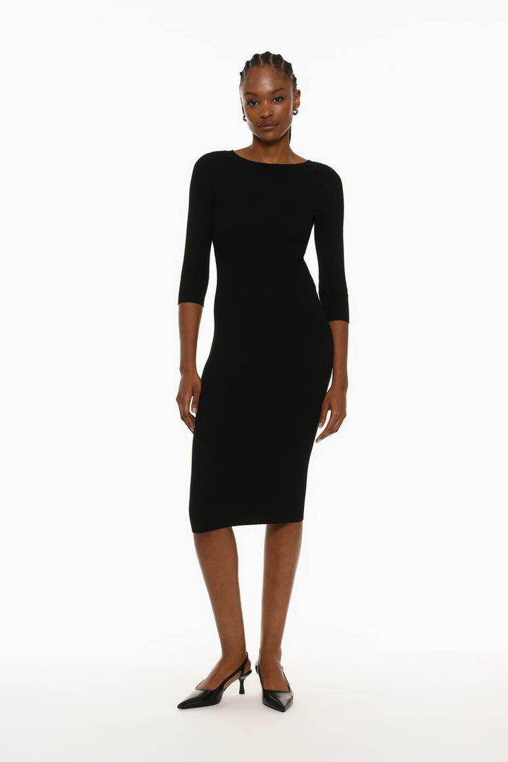 Full body front view of a woman wearing a black ribbed midi dress

