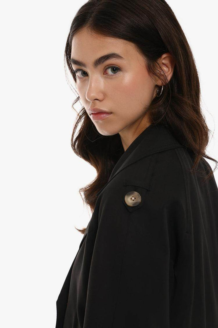 Side view of the women's black short oversize trench coat

