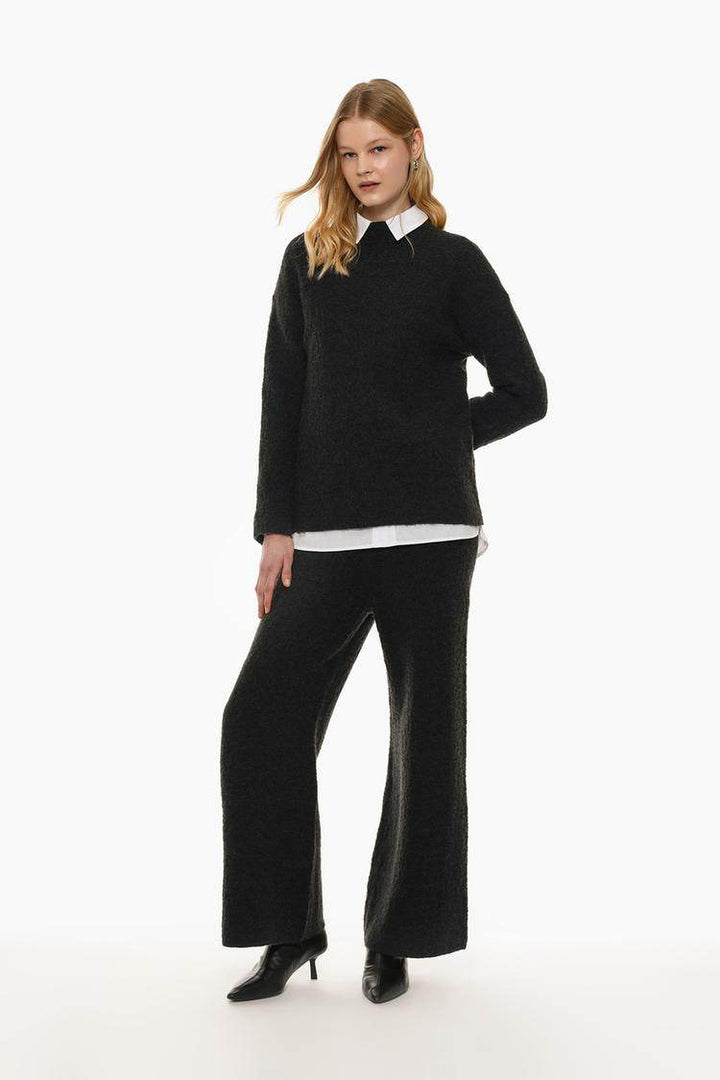 Full body front view of woman wearing black textured knit sweater

