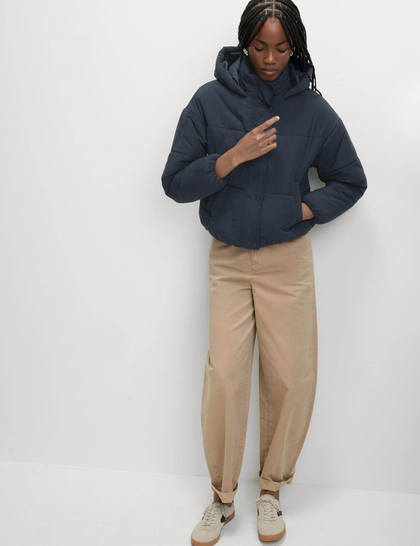 Full body front view of a woman wearing a blue hooded puffer jacket

