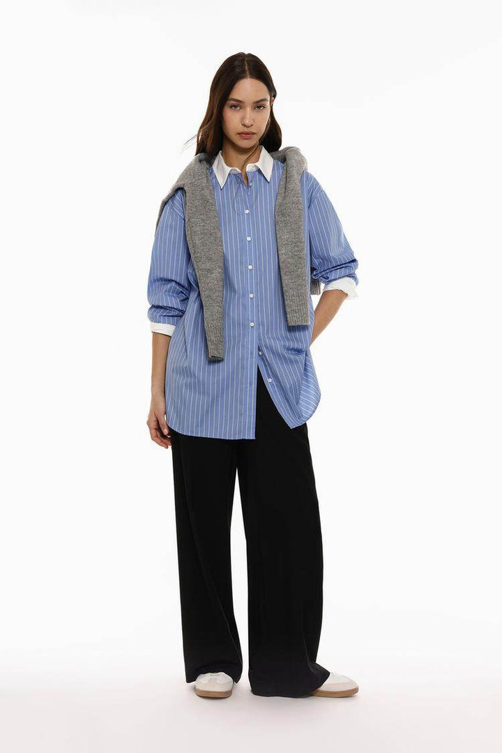 Full body front view of woman wearing blue oversized shirt

