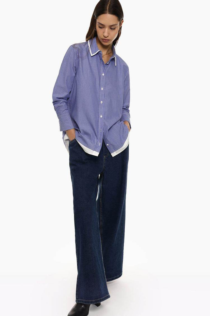 Full body front view of woman wearing blue striped shirt

