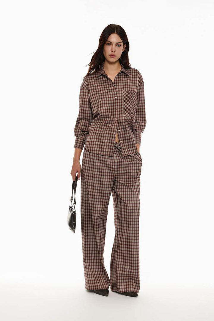 Full body front view of woman wearing brown checked shirt

