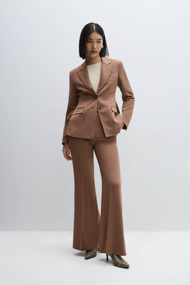 Full body view of a woman wearing a tailored brown fitted blazer

