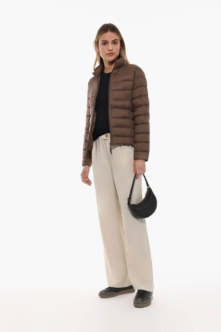 Full body front view of woman wearing brown lightweight puffer jacket

