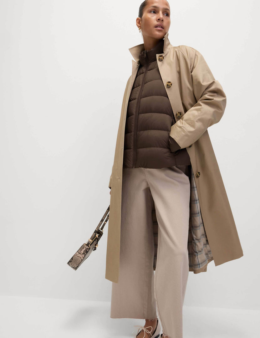 Full body front view of a woman wearing a brown puffer jacket

