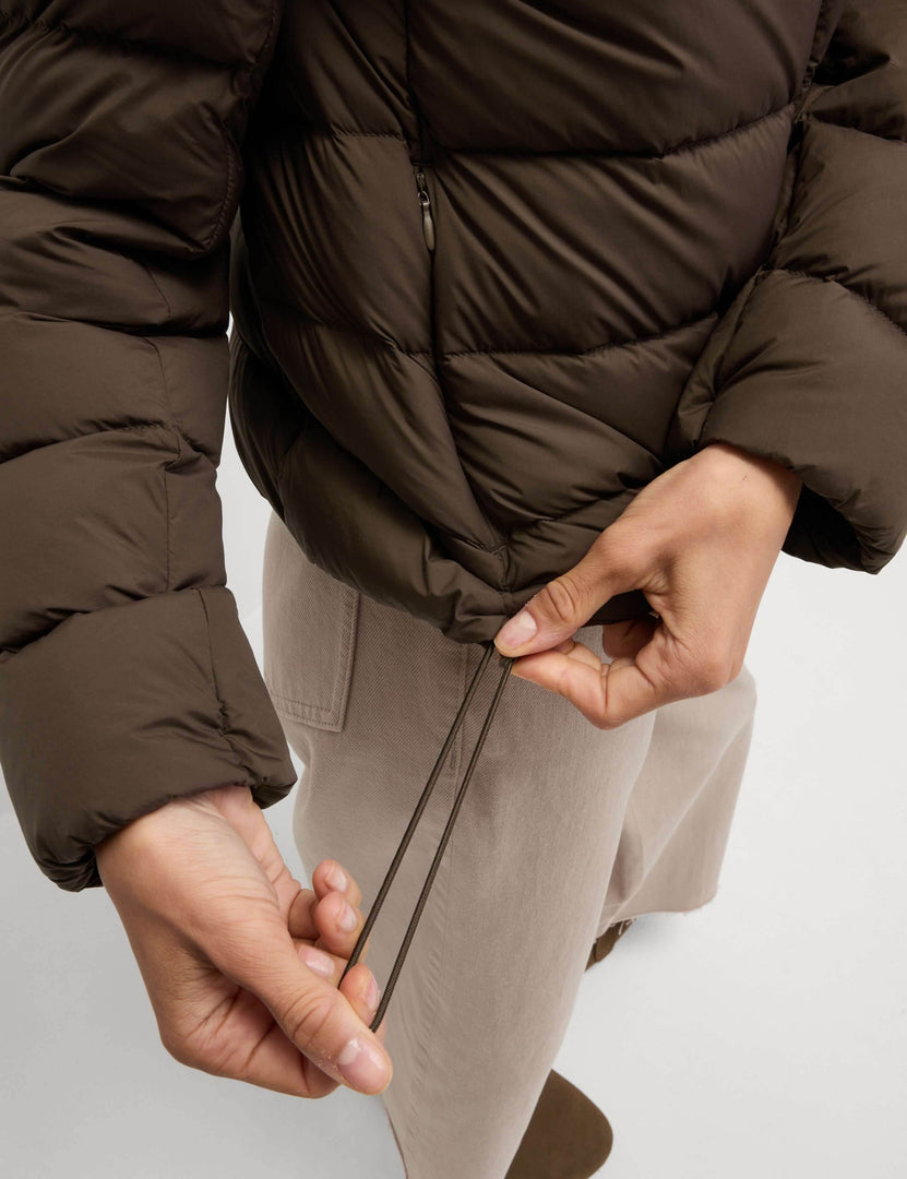 Close-up on model showing the brown puffer jacket's fabric texture

