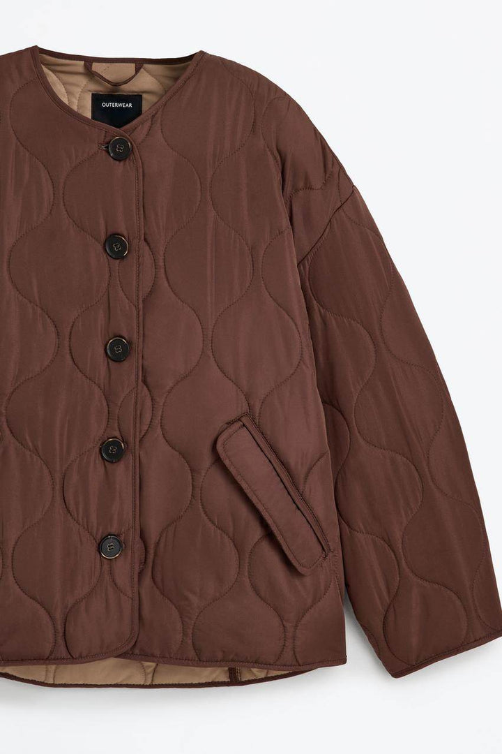 Close-up of the brown quilted jacket's fabric and stitching detail

