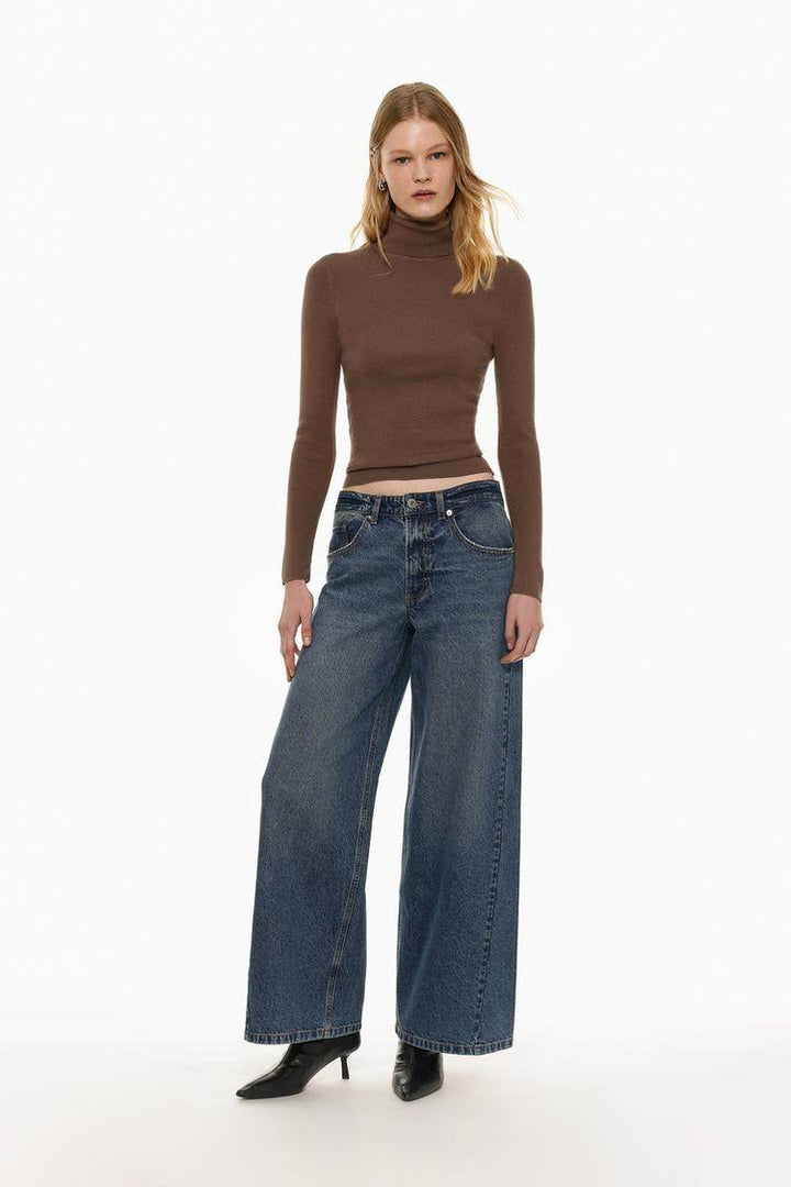 Full body front view of woman wearing brown turtleneck sweater

