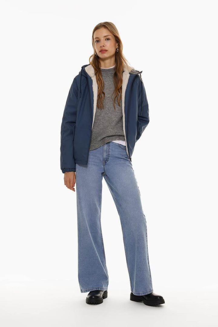 Full body front view of woman wearing dark blue rubberised parka

