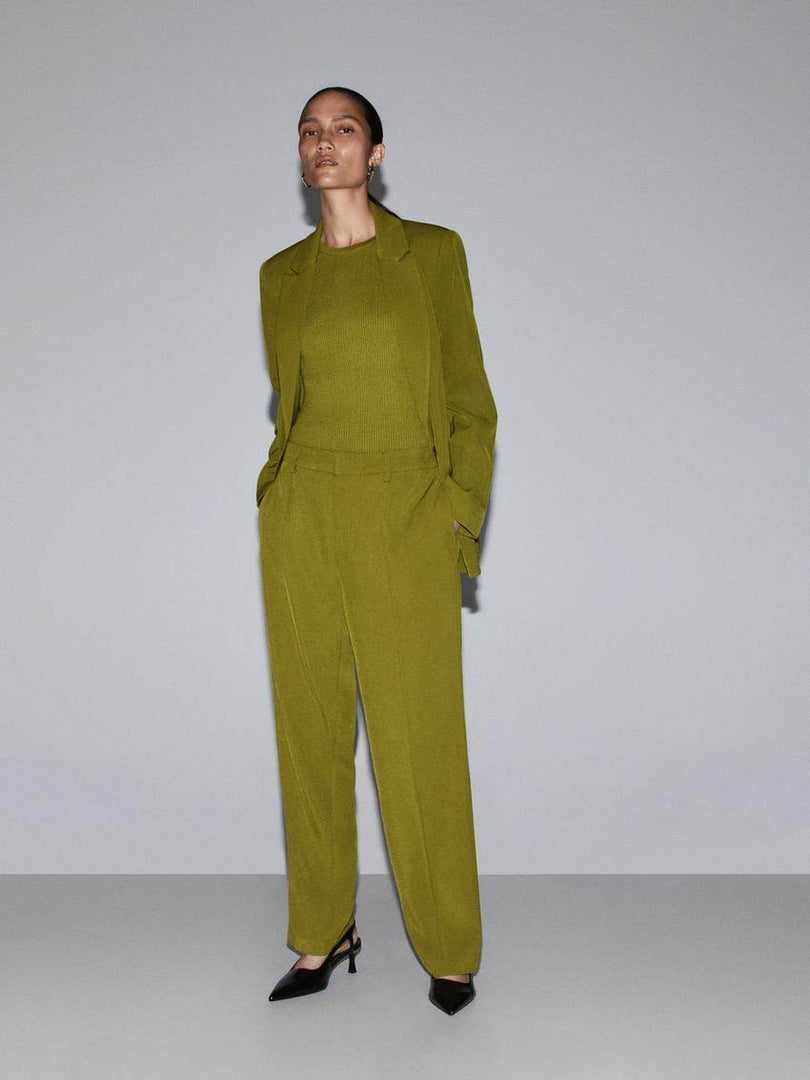 Full body front view of a woman in a green blazer

