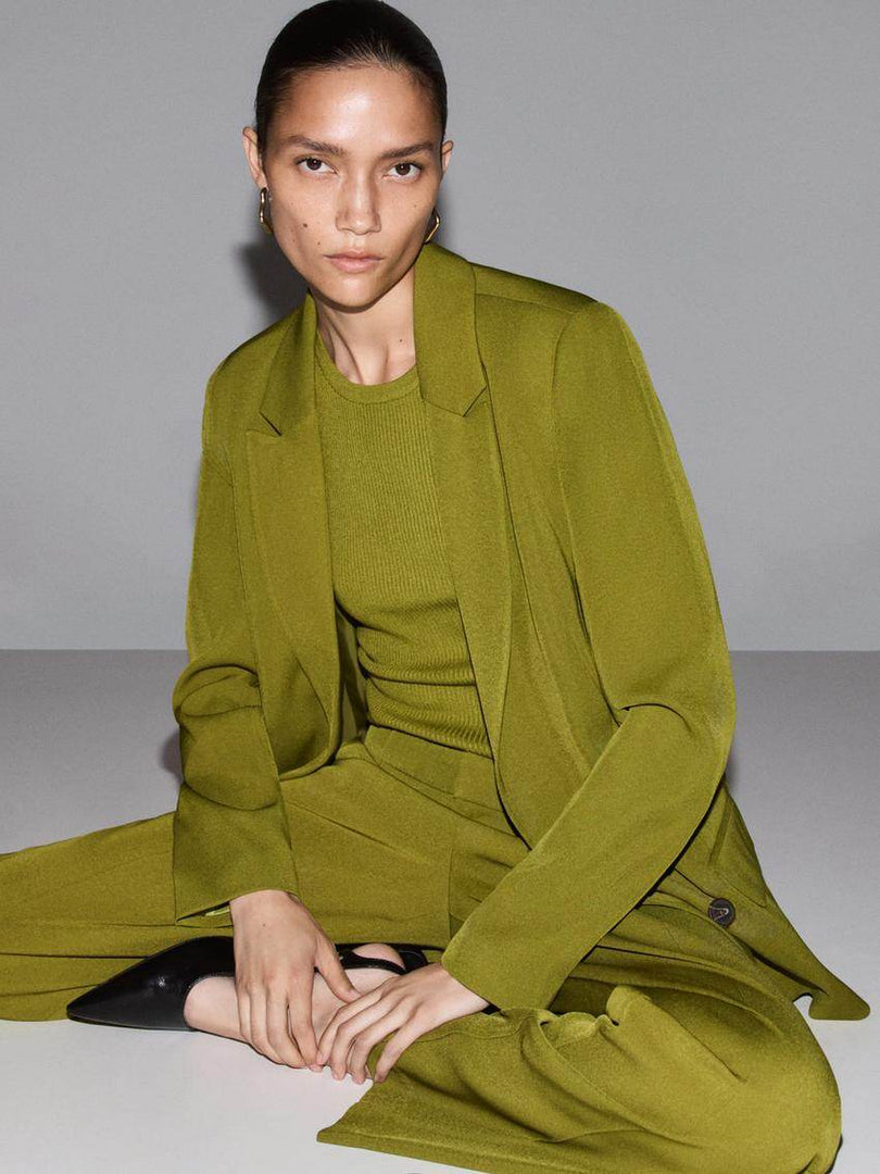 Front view of a woman sitting down wearing a green blazer

