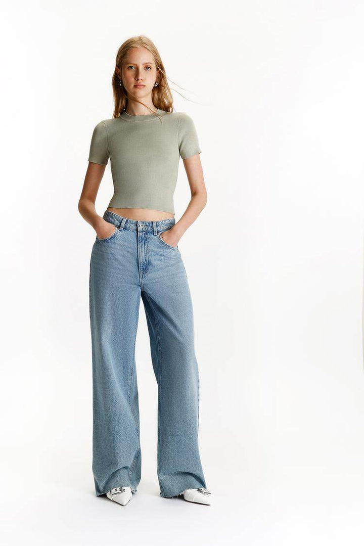 Full body front view of woman wearing green ribbed knit t-shirt

