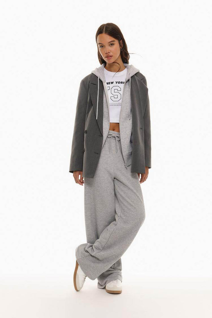 Full body front view of woman wearing grey hooded jacket

