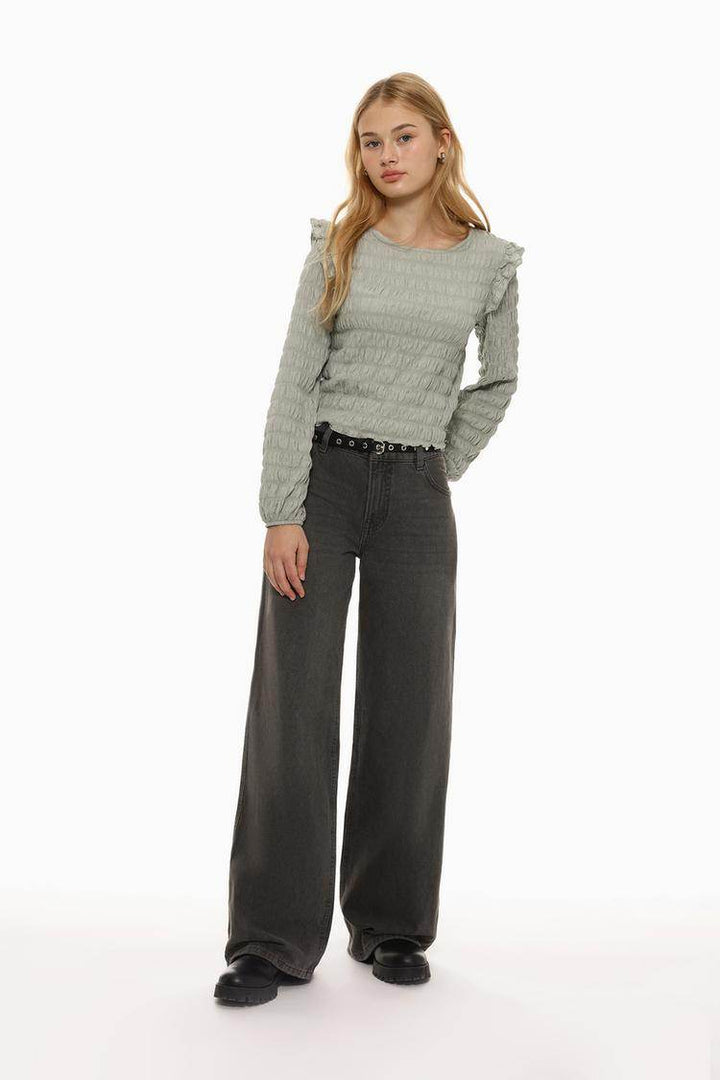 Full body front view of woman wearing grey ruffle blouse

