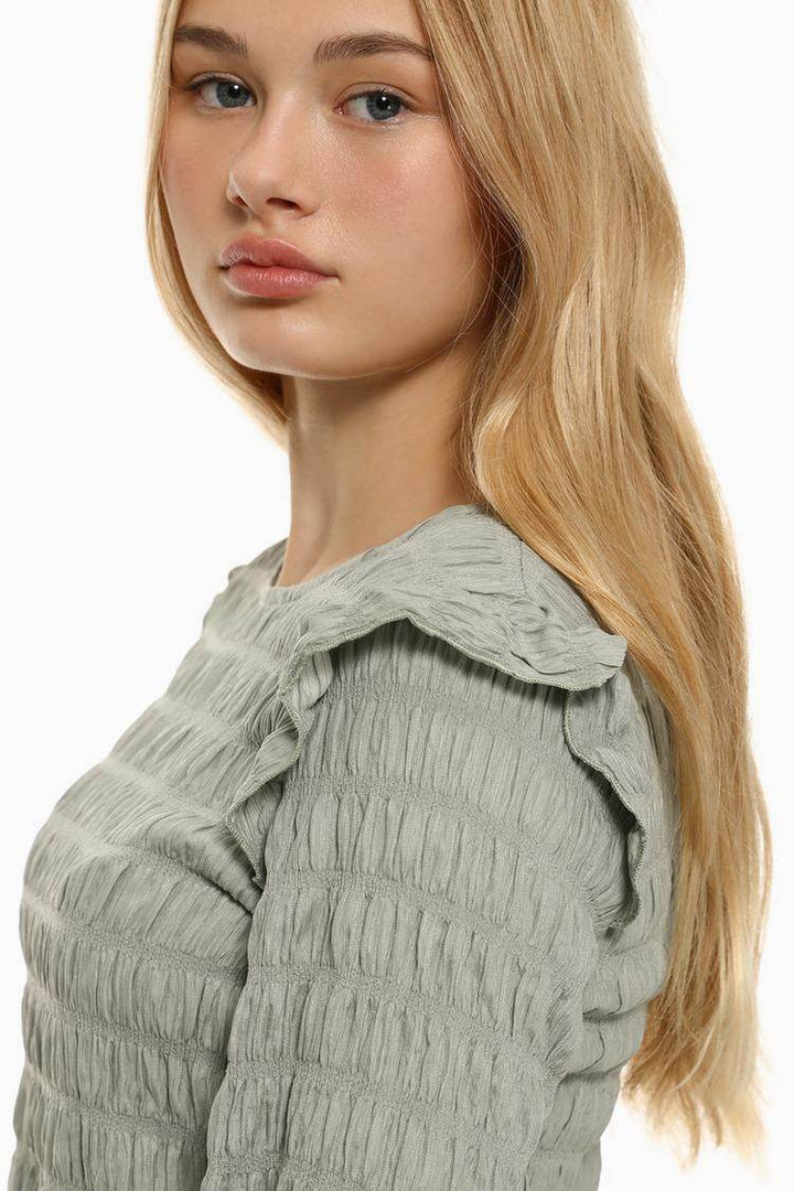 Side view of the women's grey ruffle blouse

